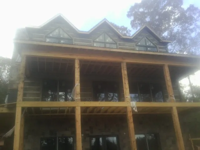 Dormers and porch framing on a large log home under construction — Roof Coating work by our crew in Shelby