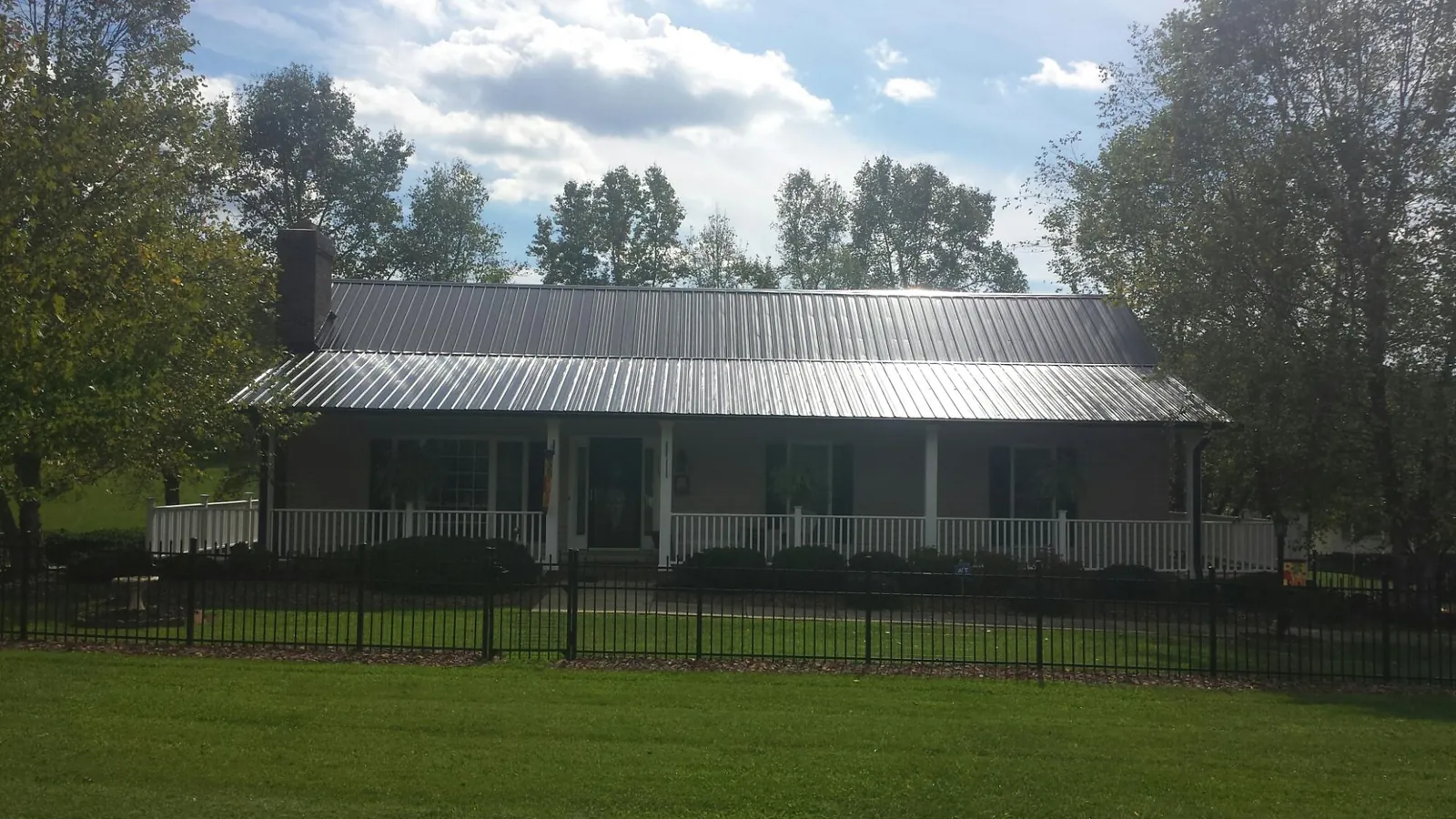 Gray metal roof on a brick ranch with a full width front porch — Gutter Guard Installation work by our crew in Shelby